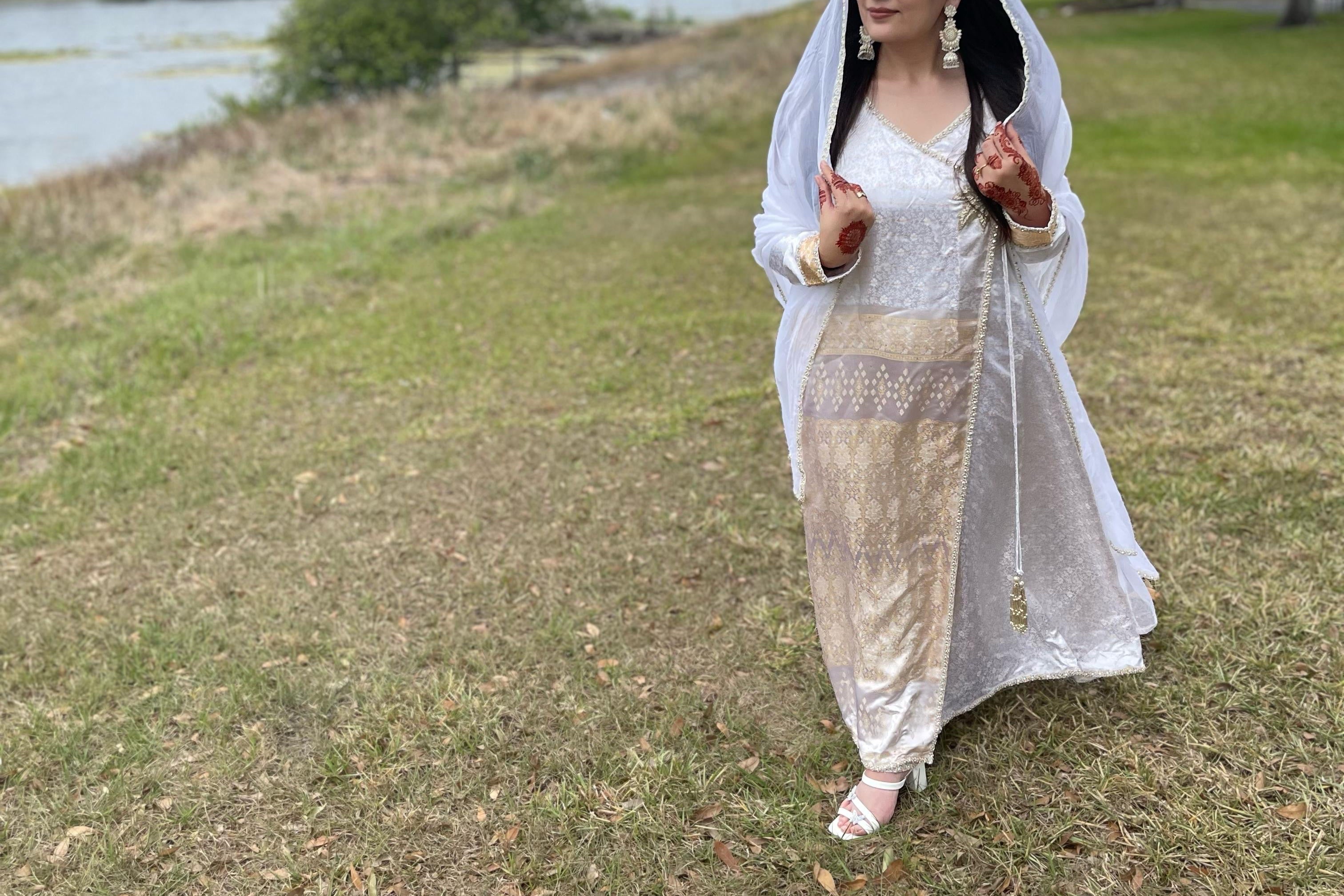 Woman in traditional outfit standing on grass with a scenic background